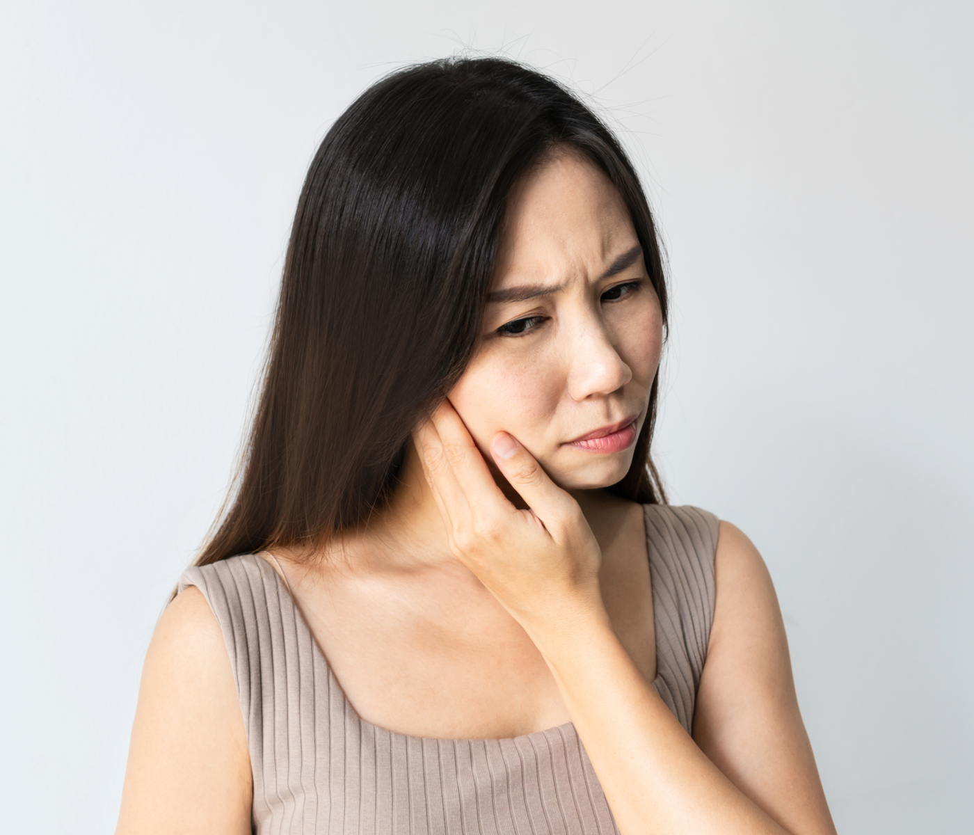 woman in a tank top feeling her face